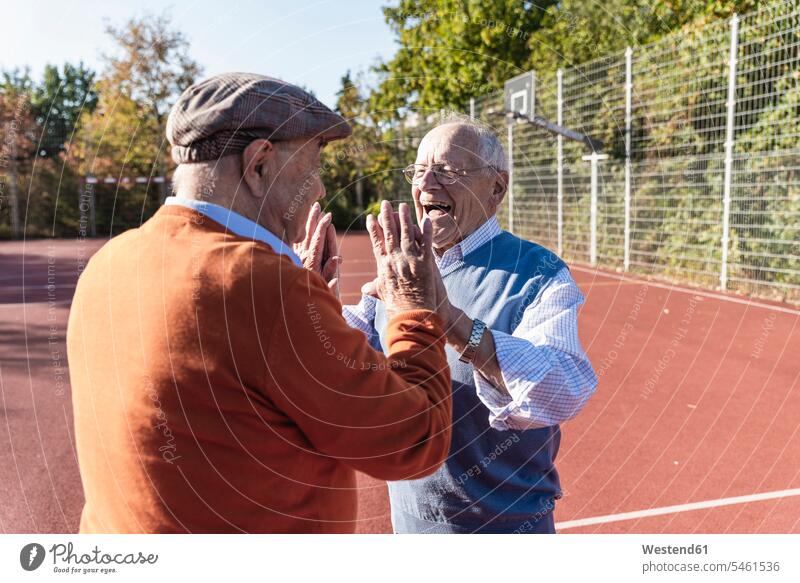 Zwei fitte Senioren beim High Fiving auf einem Basketballfeld abklatschen High Five sportlich spielen Fitness Gesundheit gesund Basketballplatz Basketballfelder