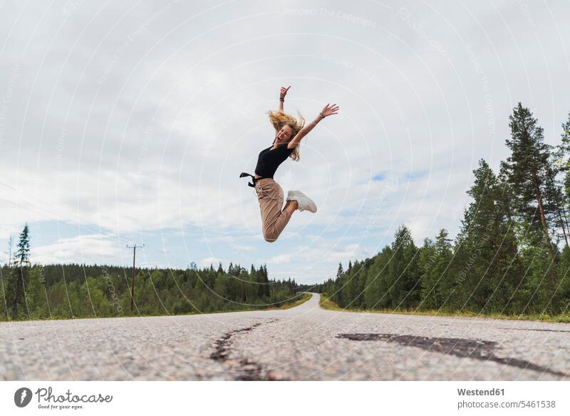 Finnland, Lappland, ausgelassene junge Frau springt in ländlicher Landschaft Landschaften weiblich Frauen springen hüpfen Ausgelassenheit Erwachsener erwachsen