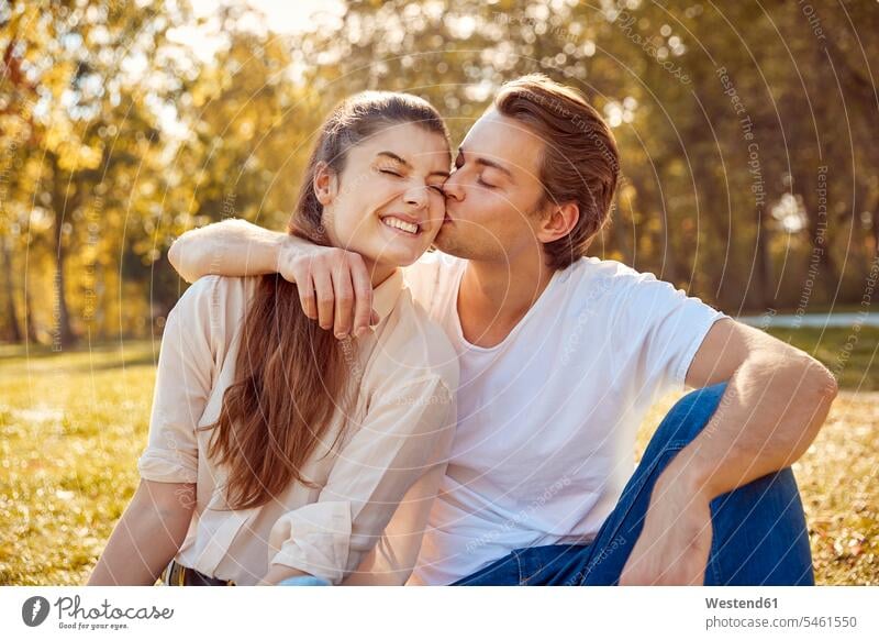 Glückliches junges Paar küssen in einem Park Parkanlagen Parks Küsse Kuss glücklich glücklich sein glücklichsein Pärchen Paare Partnerschaft Mensch Menschen