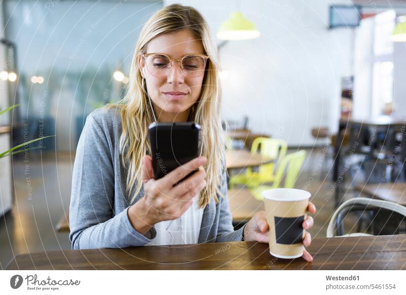 Junge Frau schreibt mit ihrem Handy SMS, während sie im Café Kaffee trinkt geschäftlich Geschäftsleben Geschäftswelt Geschäftsperson Geschäftspersonen