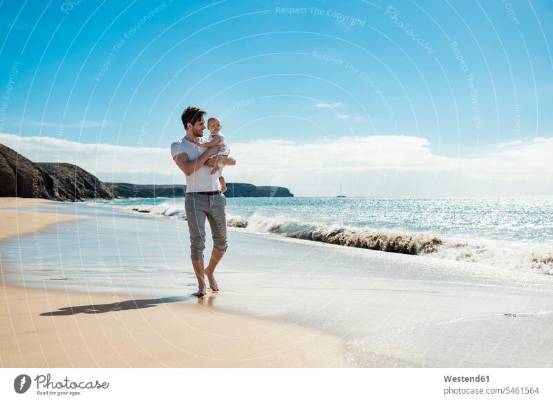 Spanien, Lanzarote, Vater trägt seine kleine Tochter am Strand tragen transportieren Baby Babies Babys Säuglinge Kind Kinder Papas Väter Vati Vatis Papis