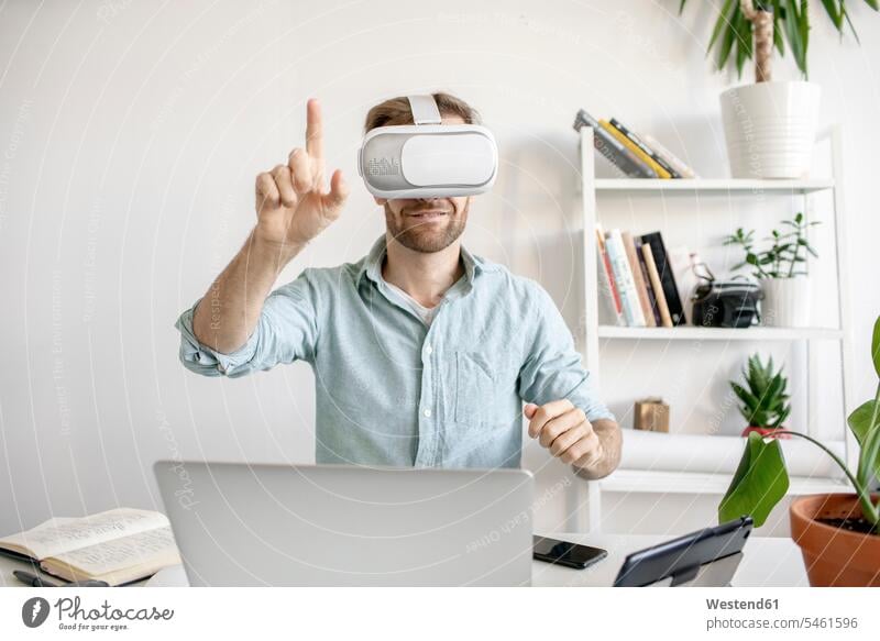 Mann mit VR-Brille am Schreibtisch im Büro Job Berufe Berufstätigkeit Beschäftigung Jobs geschäftlich Geschäftsleben Geschäftswelt Geschäftsperson
