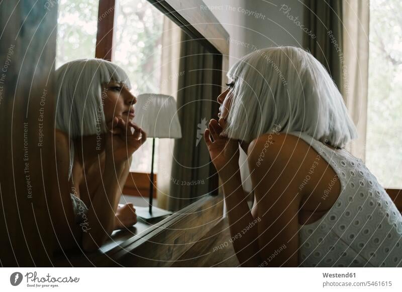 Traurige Frau, die ihr Spiegelbild im Spiegel betrachtet, während sie zu Hause am Schminktisch steht Farbaufnahme Farbe Farbfoto Farbphoto Innenaufnahme