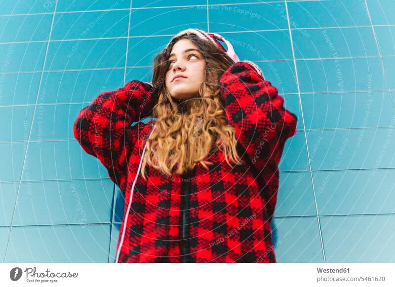 Porträt einer Teenagerin, die im Freien mit Kopfhörern Musik hört Fliese Fliesen Kacheln Kopfhoerer hoeren Farben Farbtoene Farbton Farbtöne rote roter rotes