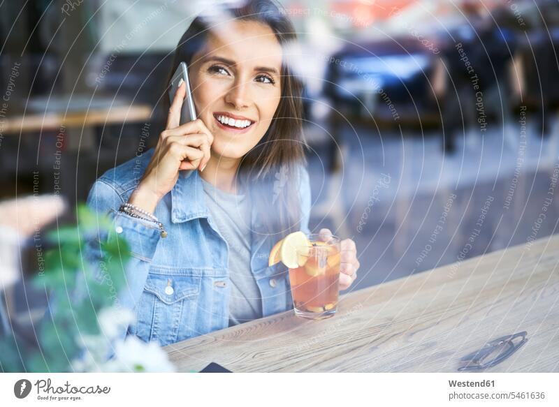 Lächelnde junge Frau am Telefon trinken Tee im Café Tees Cafe Kaffeehaus Bistro Cafes Cafés Kaffeehäuser Handy Mobiltelefon Handies Handys Mobiltelefone