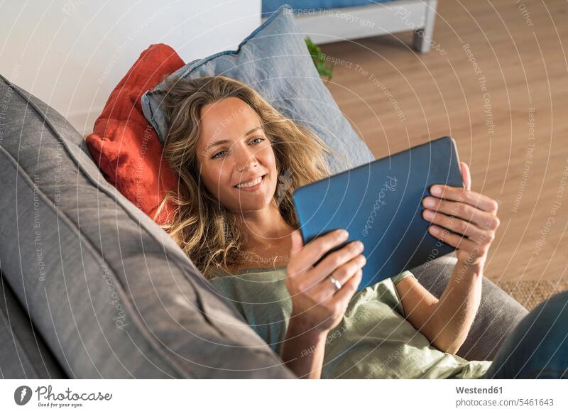 Glückliche Frau realxing auf Couch zu Hause mit Tablette entspannt entspanntheit relaxt Tablet Computer Tablet-PC Tablet PC iPad Tablet-Computer Zuhause daheim