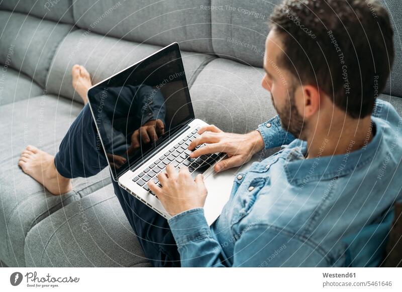 Schrägansicht eines Geschäftsmannes mit einem Laptop bei der Arbeit von zu Hause während des Ausbruchs der Coronavirus-Pandemie, Almeria, Spanien, Europa