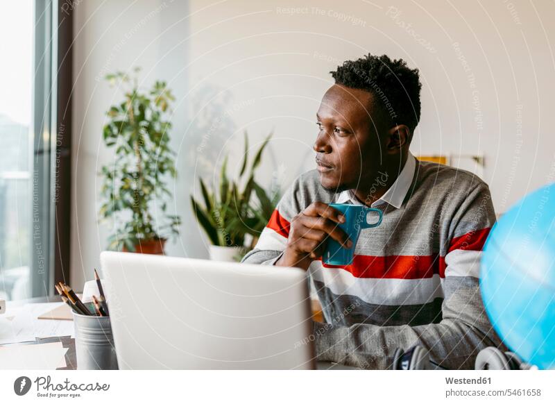 Nachdenklicher Geschäftsmann schaut weg, während er zu Hause bei einer Kaffeetasse sitzt Farbaufnahme Farbe Farbfoto Farbphoto Innenaufnahme Innenaufnahmen