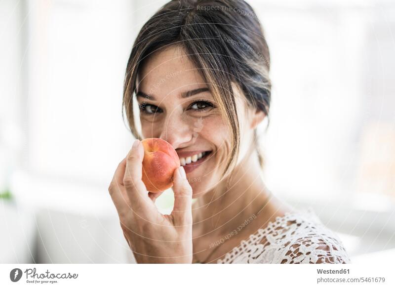 Lachende Frau, die an einer Aprikose riecht riechen Küche Küchen Aroma aromatisch Marille Aprikosen Marillen Gesundes Essen halten reife Frau reife Frauen Obst