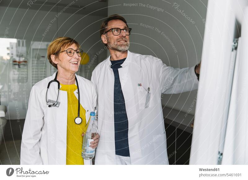 Zwei Ärzte diskutieren im Smart Board Job Berufe Berufstätigkeit Beschäftigung Jobs Gesundheit Gesundheitswesen medizinisch Stethoskope Brillen reden zufrieden