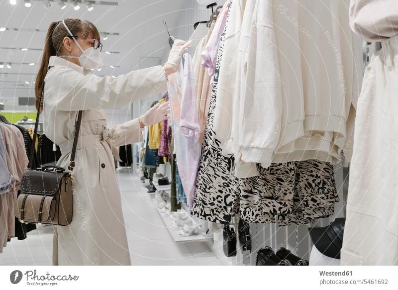 Frau mit Gesichtsmaske und Einweghandschuhen beim Einkaufen in einem Modegeschäft Taschen Handtaschen Brillen Kauf shoppen shopping Gesundheit Gesundheitswesen
