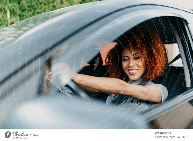 Lächelnde junge Frau mit Afro-Haaren fährt Auto durch Fenster gesehen Farbaufnahme Farbe Farbfoto Farbphoto Freizeitbeschäftigung Muße Zeit Zeit haben