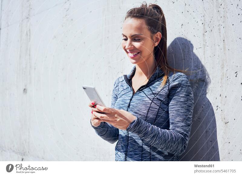 Porträt einer glücklichen Frau, die ihr Smartphone benutzt Handy Mobiltelefon Handies Handys Mobiltelefone weiblich Frauen Joggerin Joggerinnen iPhone