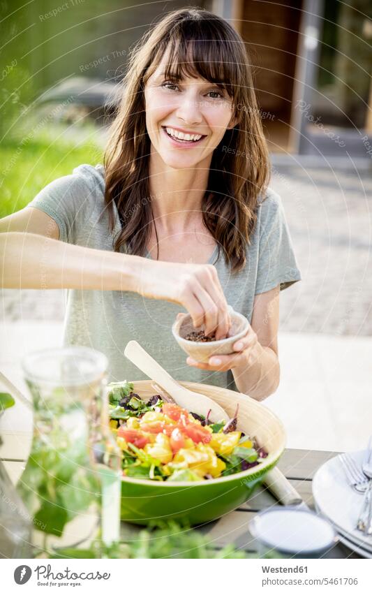 Porträt einer lächelnden Frau, die einen Salat auf einem Gartentisch zubereitet Leute Menschen People Person Personen Europäisch Kaukasier kaukasisch 1 Ein