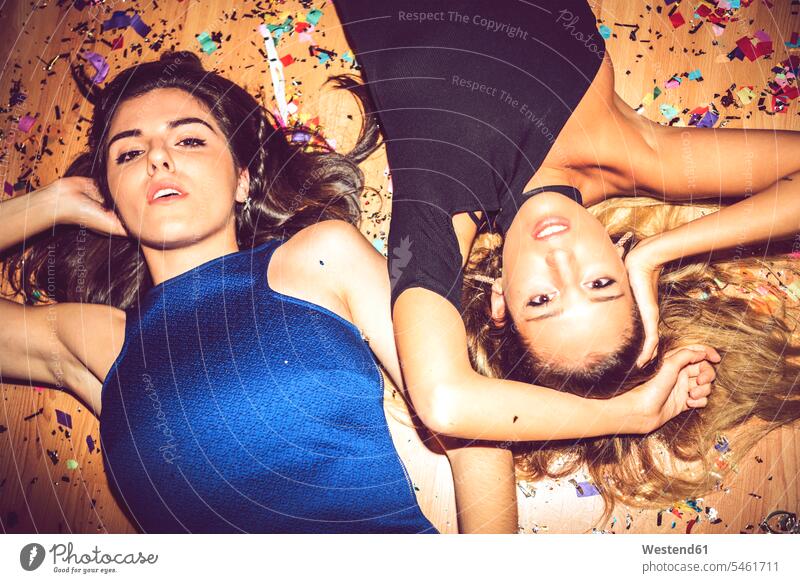 Freundinnen liegen mit Konfetti bedeckt auf dem Boden in Party Farbaufnahme Farbe Farbfoto Farbphoto Innenaufnahme Innenaufnahmen drinnen Freizeitbeschäftigung