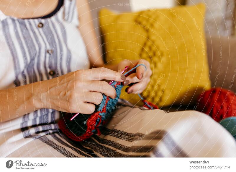 Reife Frau strickt, während sie zu Hause auf dem Sofa sitzt Farbaufnahme Farbe Farbfoto Farbphoto Innenaufnahme Innenaufnahmen innen drinnen Freizeitkleidung