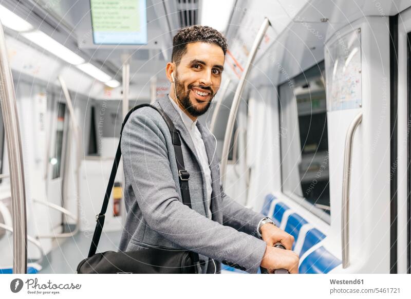 Porträt eines lächelnden jungen Geschäftsmannes mit Kopfhörern in der U-Bahn geschäftlich Geschäftsleben Geschäftswelt Geschäftsperson Geschäftspersonen