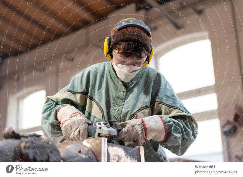 Kunstgießerei, Gießereiarbeiterin poliert Metall polieren schleifen Arbeiter Schleifmaschine Schleifmaschinen Beruf Berufstätigkeit Berufe Beschäftigung Jobs