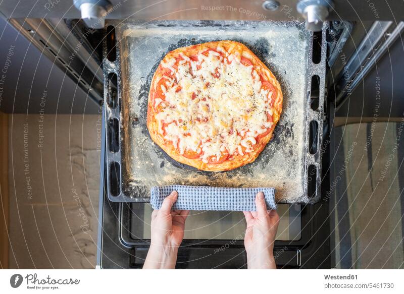 Frauenhände nehmen Tablett mit gebackener Pizza aus dem Ofen daheim zu Hause heiss Hitze Muße Lifestyles Aktivitaet Aktivität Handeln Essen Essen und Trinken