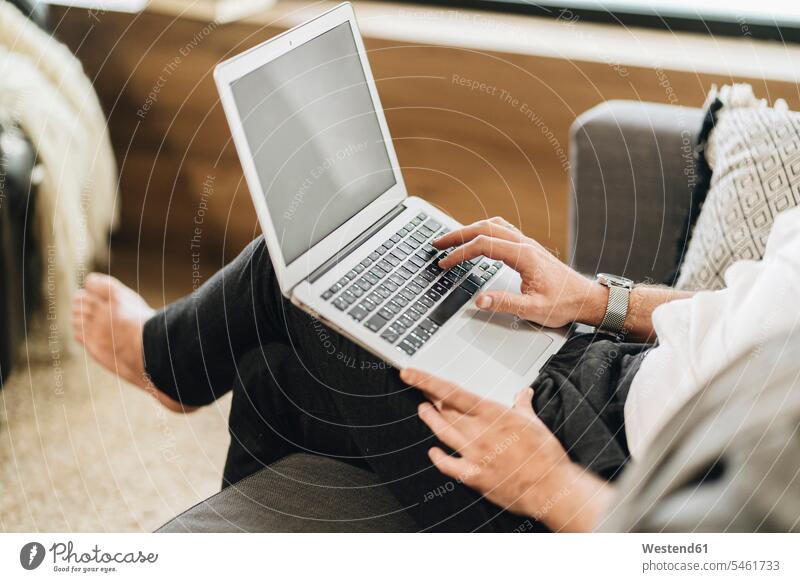 Mann sitzt zu Hause, benutzt Laptop, Nahaufnahme casual Freizeitbekleidung daheim drinnen Innenaufnahmen Wohnen Wohnraum Wohnräume Wohnung Wohnungen Technik
