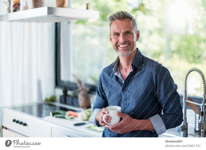 Porträt eines lächelnden reifen Mannes zu Hause in der Küche bei einer Tasse Kaffee Portrait Porträts Portraits Männer männlich Kaffeetasse Kaffeetassen