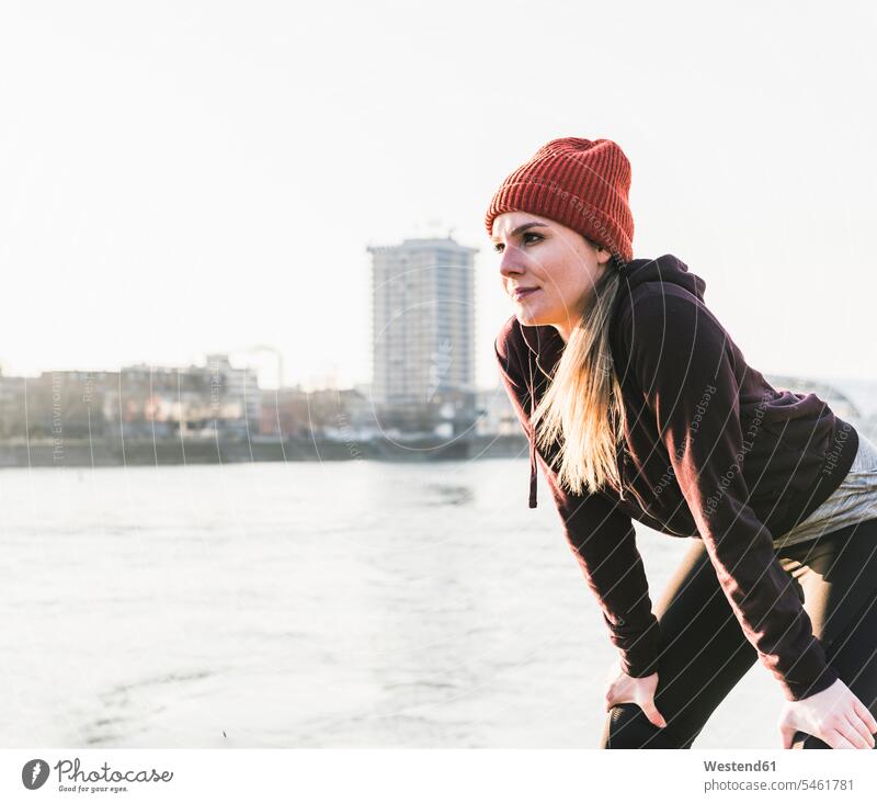Sportliche junge Frau bei einer Pause am Flussufer in der Stadt sportlich weiblich Frauen Fluesse Fluß Flüsse staedtisch städtisch Ufer Erwachsener erwachsen