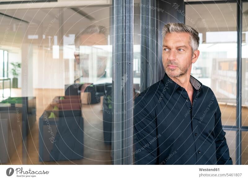 Buinessman im Büro stehend, an Glaswand gelehnt, nachdenkend Leute Menschen People Person Personen Europäisch Kaukasier kaukasisch 1 Ein ein Mensch eine