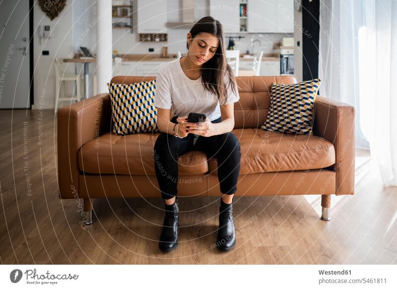 Junge Frau auf der Couch zu Hause mit Mobiltelefon Leute Menschen People Person Personen erwachsen jung Millennial 20 - 30 Jahre 20 bis 30 20 bis 30 Jahre 20-30