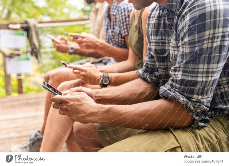 Italien, Massa, Wanderer in den Alpi Apuane Bergen, die auf ihre Smartphones schauen und auf einer Bank sitzen Freunde ansehen Sitzbänke Bänke Sitzbank Handy
