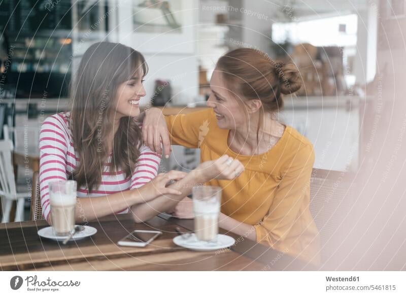 Zwei Freundinnen treffen sich in einem Café und unterhalten sich Cafe Kaffeehaus Bistro Cafes Kaffeehäuser Treffen Begegnung sprechen reden sitzen sitzend sitzt