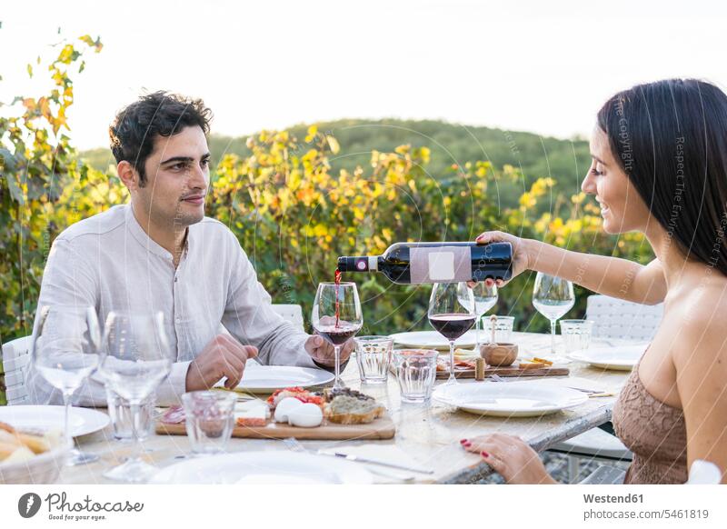 Italien, Toskana, Siena, junges Paar beim Abendessen in einem Weinberg mit Rotwein Rotweine Weingaerten Weingarten Weingärten Weinberge Pärchen Paare