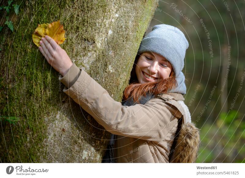 Porträt von lächelnden Teenager-Mädchen umarmt Baumstamm in herbstlichen Wald Bäume Baeume Teenagerin junges Mädchen Teenagerinnen weiblich junge Frau Portrait