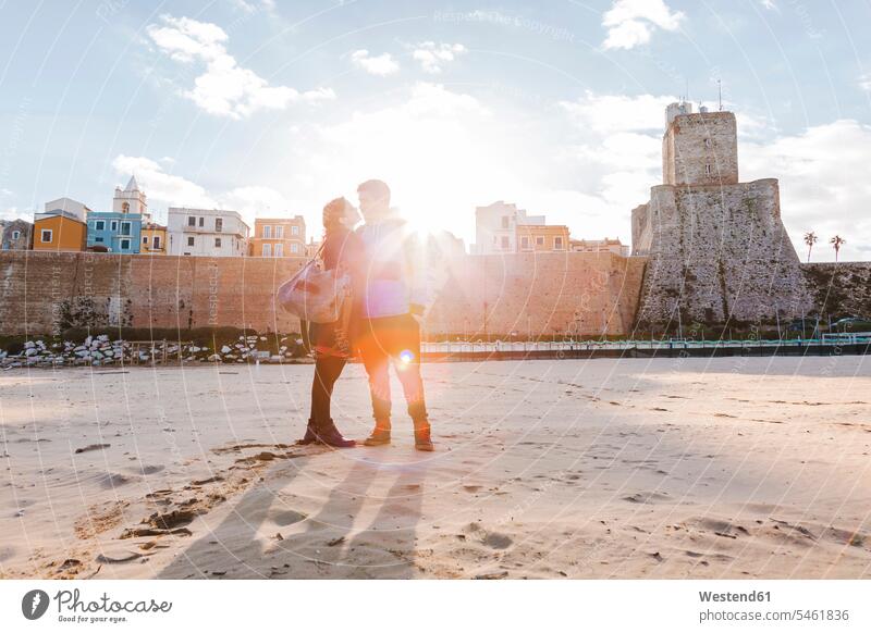 Italien, Molise, Termoli, junges Paar am Strand bei Sonnenaufgang Beach Straende Strände Beaches Pärchen Paare Partnerschaft Zweisamkeit verliebt romantisch