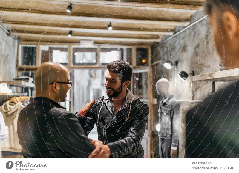 Zwei lächelnde Männer treffen sich in modernem Herrenbekleidungsgeschäft Mann männlich Geschäft Shop Laden Läden Geschäfte Shops Herrenmode Kunde Kunden