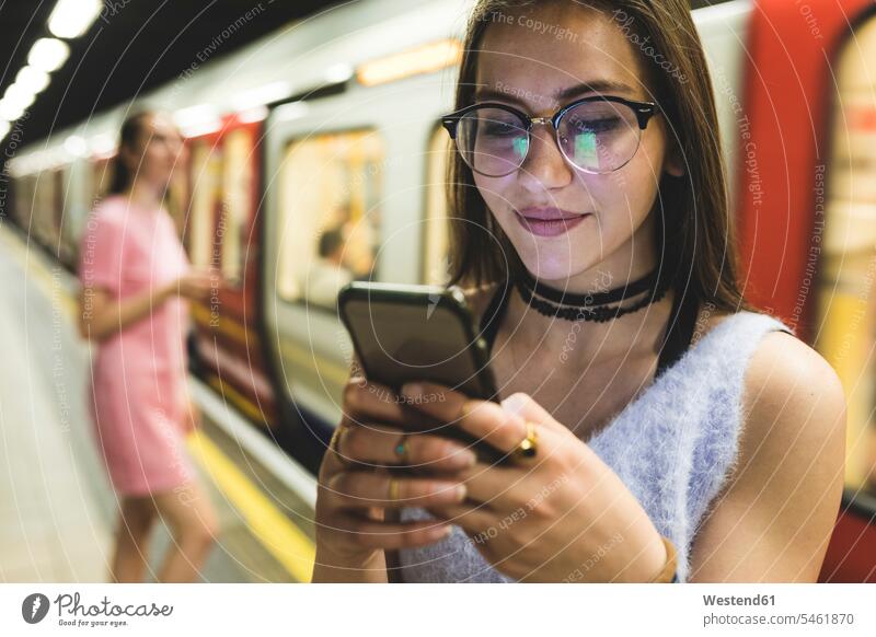 Teenager-Mädchen benutzt Handy in U-Bahn-Station Ubahn U-Bahnen Untergrundbahnen Ubahnen Underground Subway Mobiltelefon Handies Handys Mobiltelefone Frau