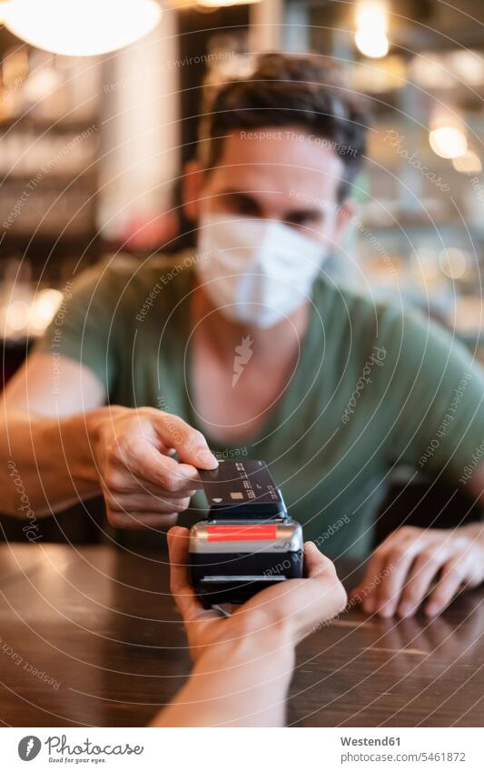 Mann mit Schutzmaske bezahlt mit Kreditkarte im Restaurant Leute Menschen People Person Personen Europäisch Kaukasier kaukasisch 2 2 Menschen 2 Personen zwei