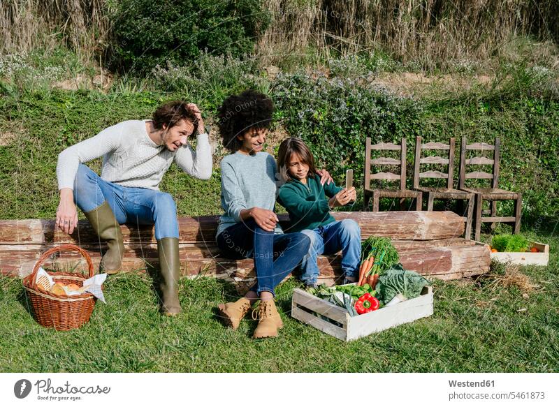 Glückliche Familie, die nach der Gemüseernte eine Pause einlegt und Selfies macht Picknick picknicken ernten Ernte Gemuese Pause machen Gemüsegarten
