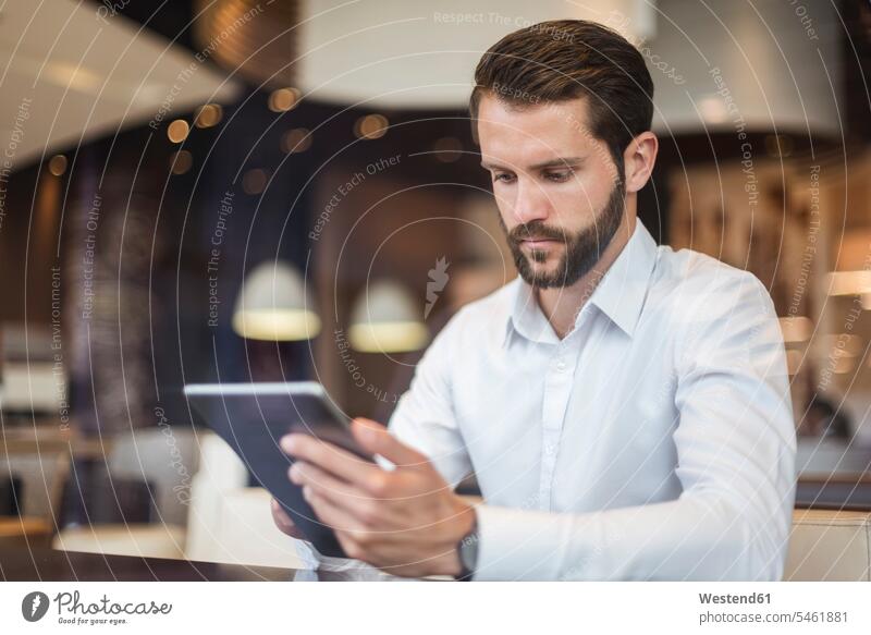 Junger Geschäftsmann benutzt Tablette in einem Cafe Businessmann Businessmänner Geschäftsmänner Tablet Computer Tablet-PC Tablet PC iPad Tablet-Computer
