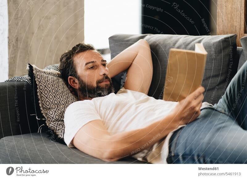 Reifer Mann liegt auf Couch, liest Buch Leute Menschen People Person Personen Europäisch Kaukasier kaukasisch 1 Ein ein Mensch eine nur eine Person single