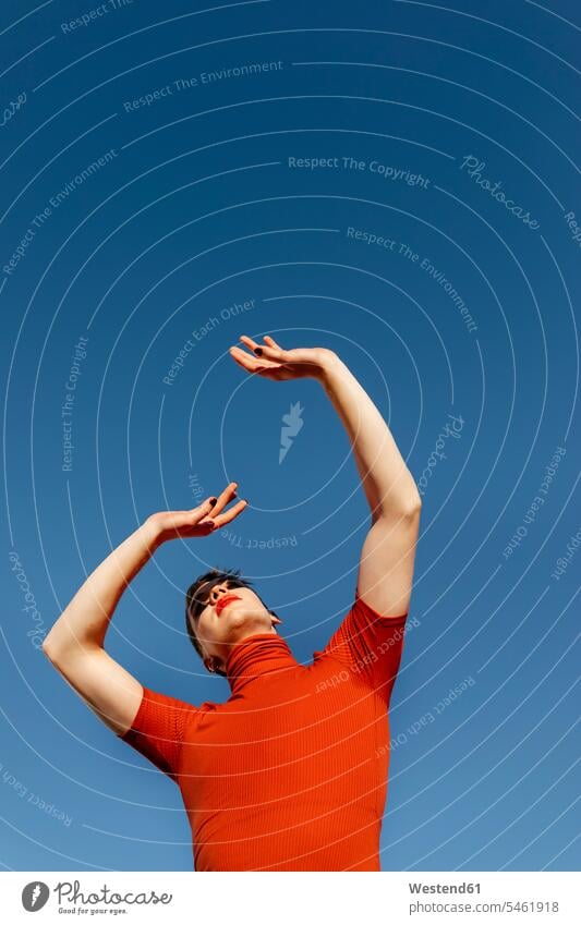 Nicht-binärer Mann mit erhobener Hand, der an einem sonnigen Tag am klaren Himmel steht Farbaufnahme Farbe Farbfoto Farbphoto Außenaufnahme außen draußen
