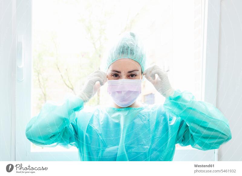 Nahaufnahme einer Krankenschwester mit chirurgischer Maske gegen das Fenster im Krankenhaus Farbaufnahme Farbe Farbfoto Farbphoto Innenaufnahme Innenaufnahmen