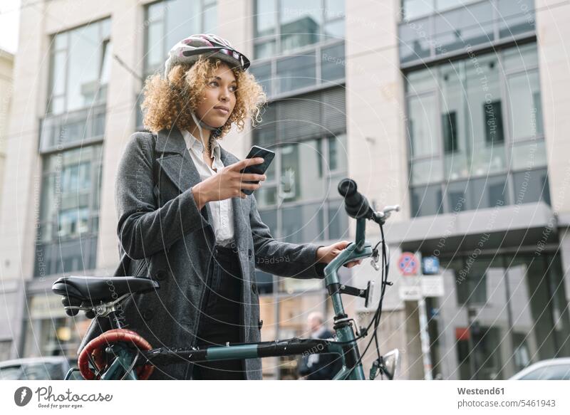 Frau mit Fahrrad und Smartphone in der Stadt, Berlin, Deutschland geschäftlich Geschäftsleben Geschäftswelt Geschäftsperson Geschäftspersonen Businessfrau