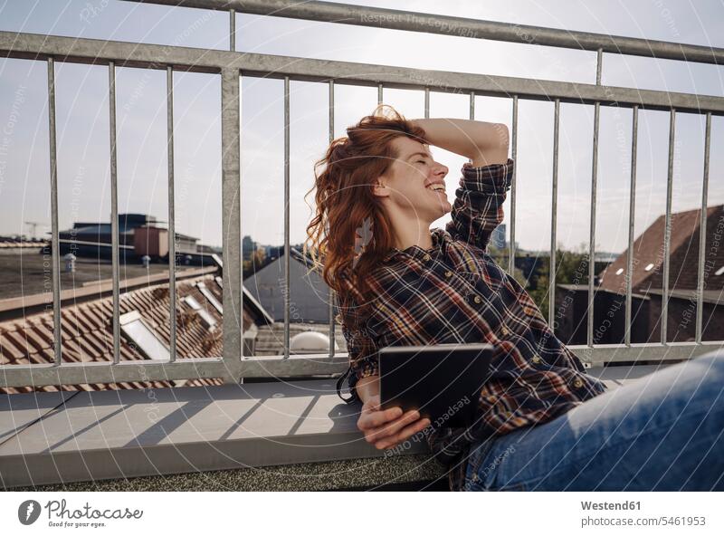 Glückliche rothaarige Frau mit Tablette entspannt auf der Dachterrasse geschäftlich Geschäftsleben Geschäftswelt Geschäftsperson Geschäftspersonen Businessfrau