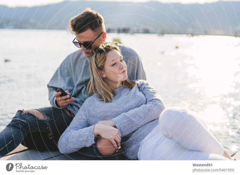 Junges Paar entspannt auf Steg am Zürichsee, Zürich, Schweiz Telekommunikation Handies Handys Mobiltelefon Mobiltelefone gefühlvoll Emotionen Empfindung