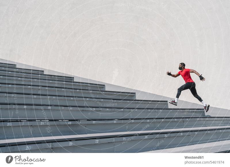 Sportler mit Gesichtsmaske beim Treppensteigen rennen Farben Farbtoene Farbton Farbtöne rote roter rotes Leistungen Dynamik dynamisch Power Muße Anreiz Ansporn