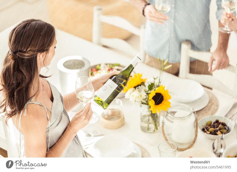 Frau hält Weinflasche während des Mittagessens Flaschen Weinflaschen Gläser Trinkglas Trinkgläser Weingläser Tische Esstische Gedecke Gedeckte Tische stehend