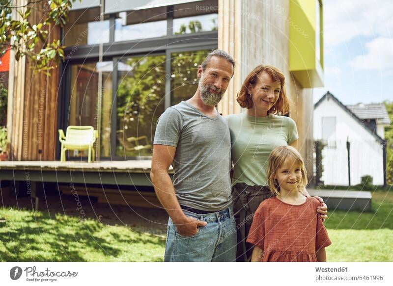 Lächelnde Familie posiert, während sie vor einem winzigen Haus im Hof steht Farbaufnahme Farbe Farbfoto Farbphoto Deutschland Freizeitbeschäftigung Muße Zeit