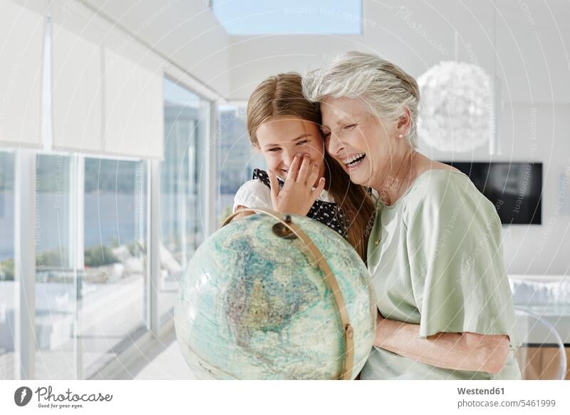Lachende Großmutter und Enkelin mit Globus in einer Villa Generation Erdkugel Globen Weltkugel freuen Frohsinn Fröhlichkeit Heiterkeit geniessen Genuss Glück