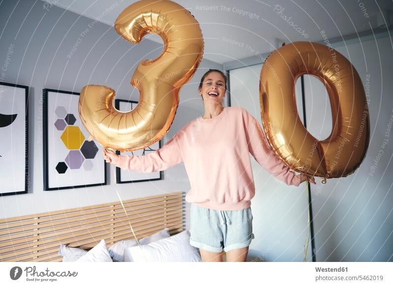 Porträt einer fröhlichen Frau mit goldenen Luftballons, die ihren Geburtstag feiert Allein alleine einzeln lächeln Bett Betten weiblich Frauen glücklich Glück