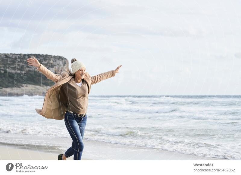 Spanien, Menorca, glückliche Seniorin beim Laufen am Strand im Winter älter Seniorinnen alt laufen rennen winterlich Winterzeit Beach Straende Strände Beaches
